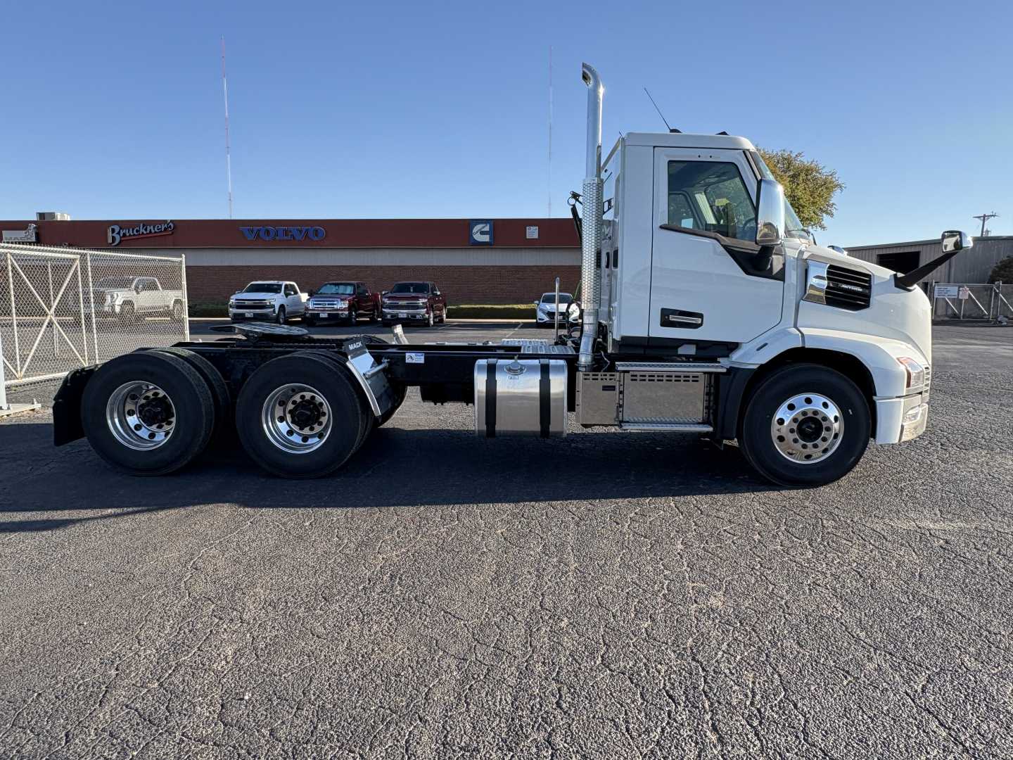 [Truck chassis] side view showing AN64T Mack truck cab with long wheelbase, dual rear axles, white cab, black chassis, fuel tanks and steps visible.