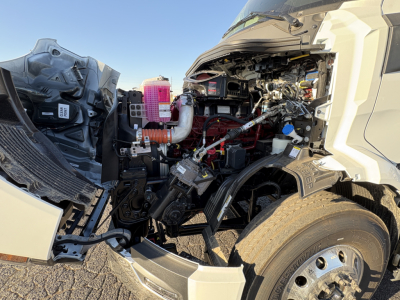 Truck engine bay of a new 2027 Mack AN64T daycab showing exposed engine components and intake tubes.