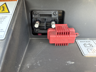 Mack AN64T truck engine bay area showing 12V red battery disconnect switch and two terminal posts.