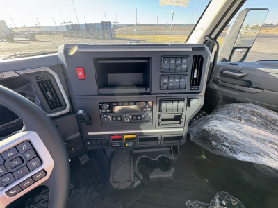 Dashboard view of a Mack AN64T truck cab showing control panels, switches, vents, and cup holders. Dashboard text is not legible.
