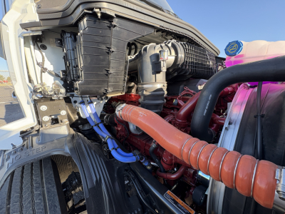 Mack AN64T engine bay with red engine, orange coolant hose, blue hoses, radiator cap, and air intake visible.