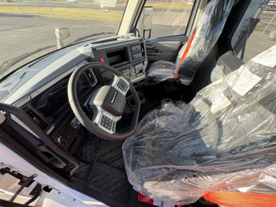 Interior of a new 2027 Mack AN64T daycab truck showing steering wheel, dashboard, and plastic-covered seats.
