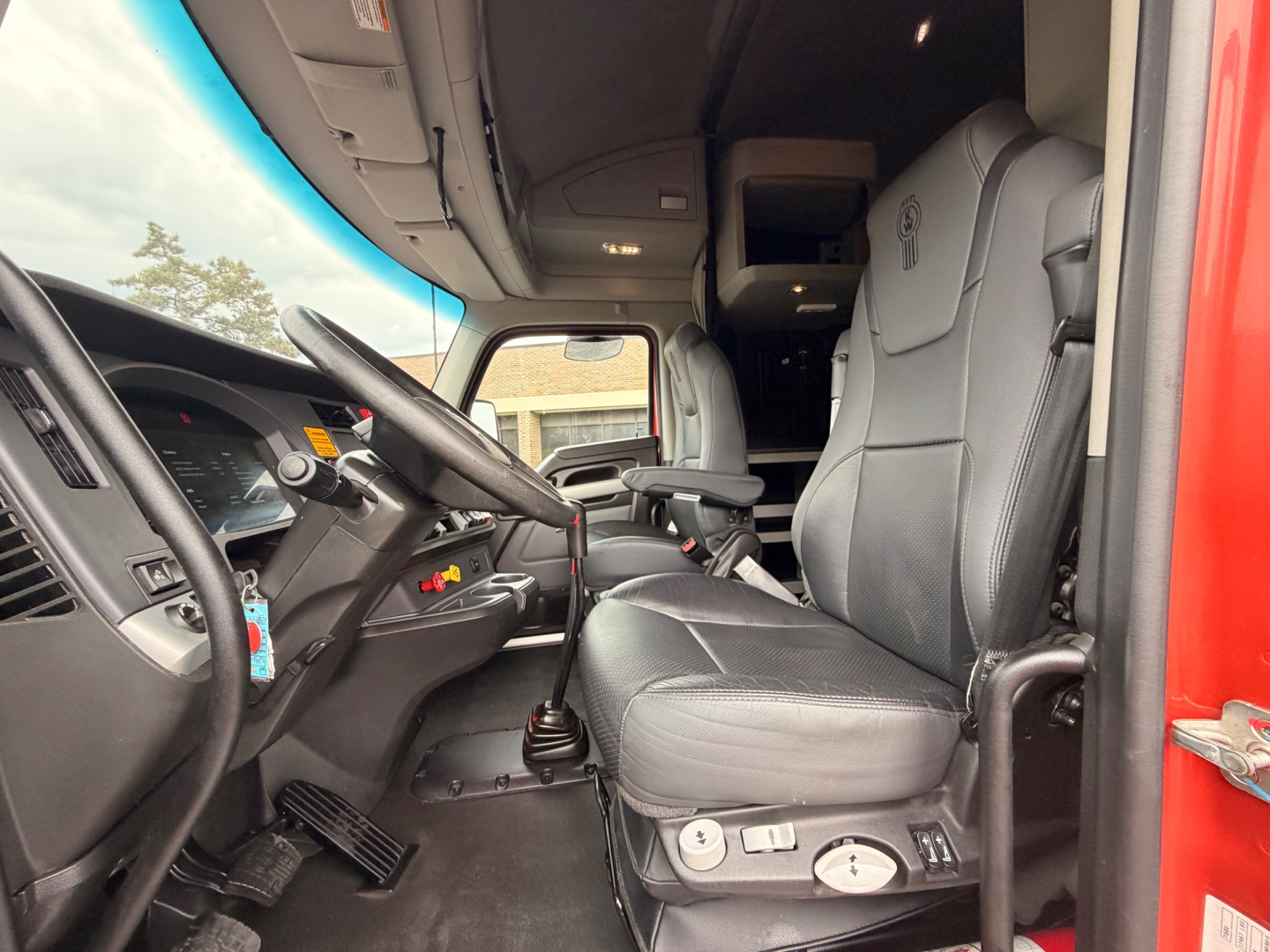 Kenworth T680 truck interior driver seat and dashboard view with steering wheel and controls.