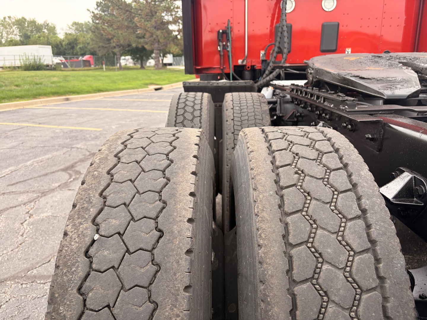 Kenworth T680 dual rear tractor tires and red cab visible from rear angle showing suspension and fifth wheel base.