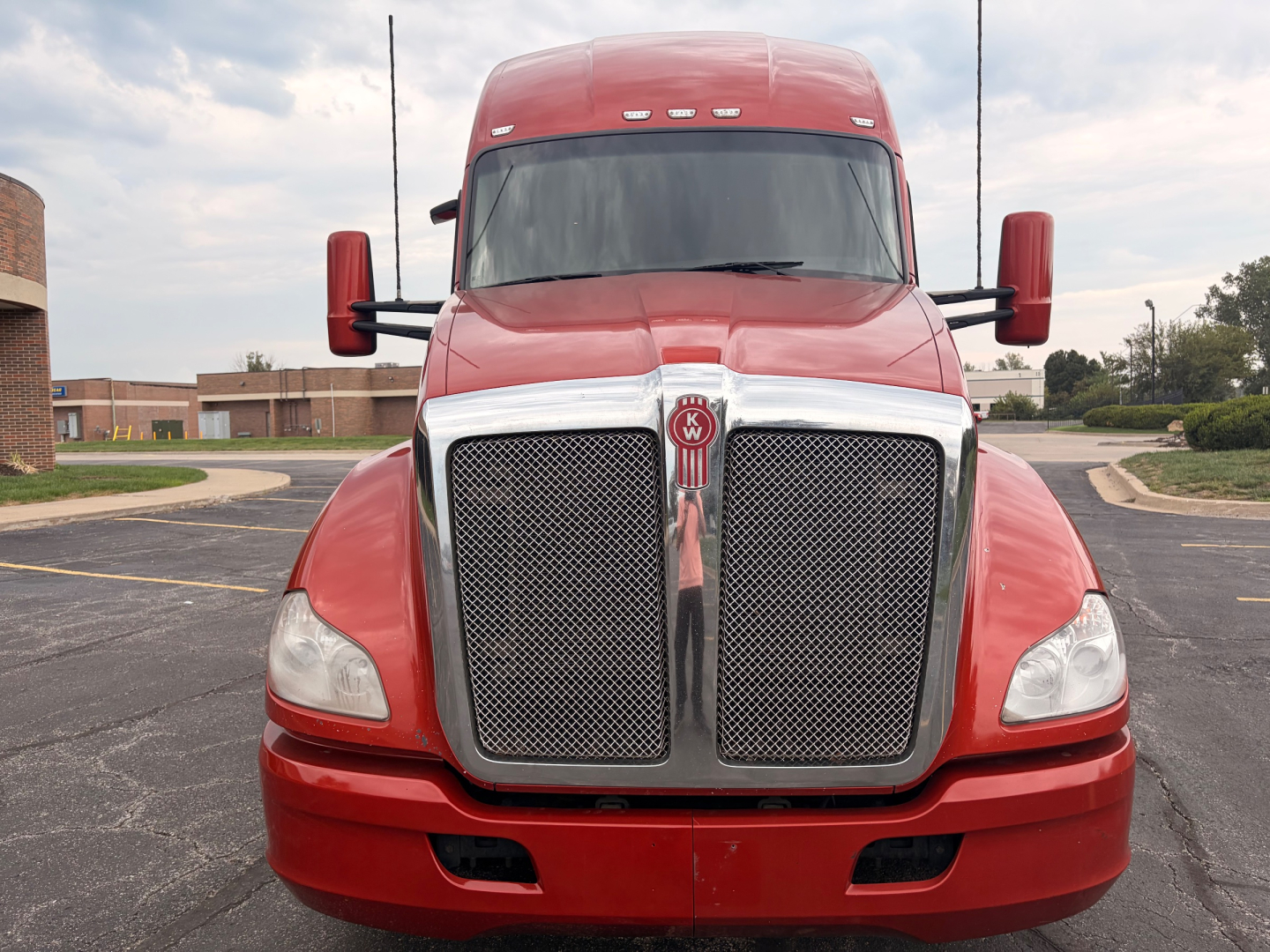 Front view of a red 2022 Kenworth T680 truck showing large chrome grille, headlights, and side mirrors.