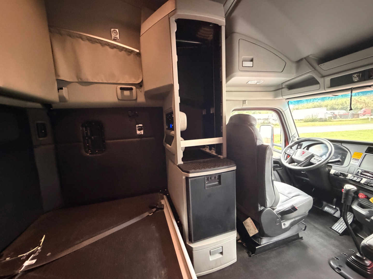 Kenworth T680 interior cab view showing sleeper area and dashboard with driver's seat and steering wheel.