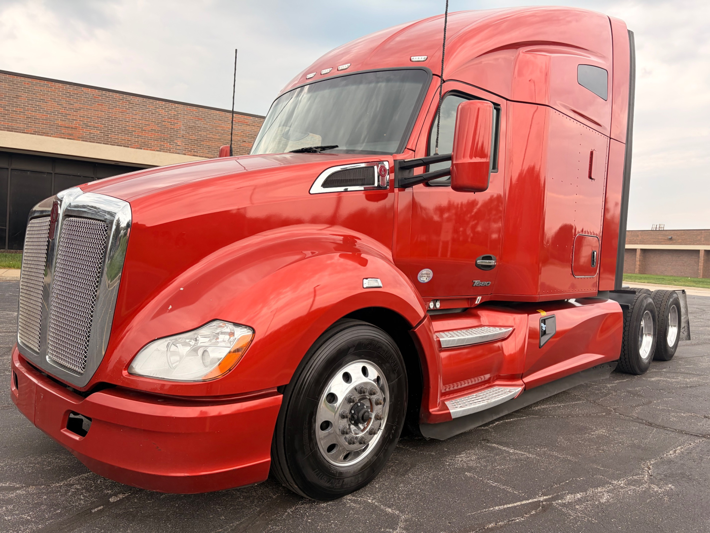 Red 2022 Kenworth T680 sleeper tractor truck profile showing cab and front grille with chrome accents.
