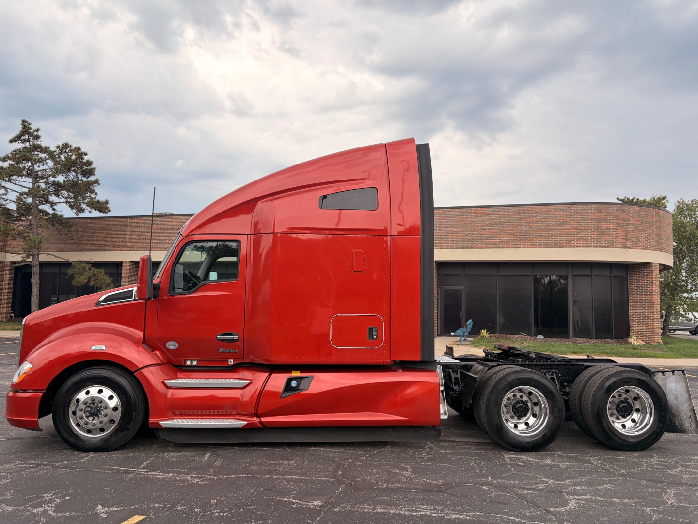 Kenworth T680 sleeper tractor side view showing red cab and chassis with dual rear axles.