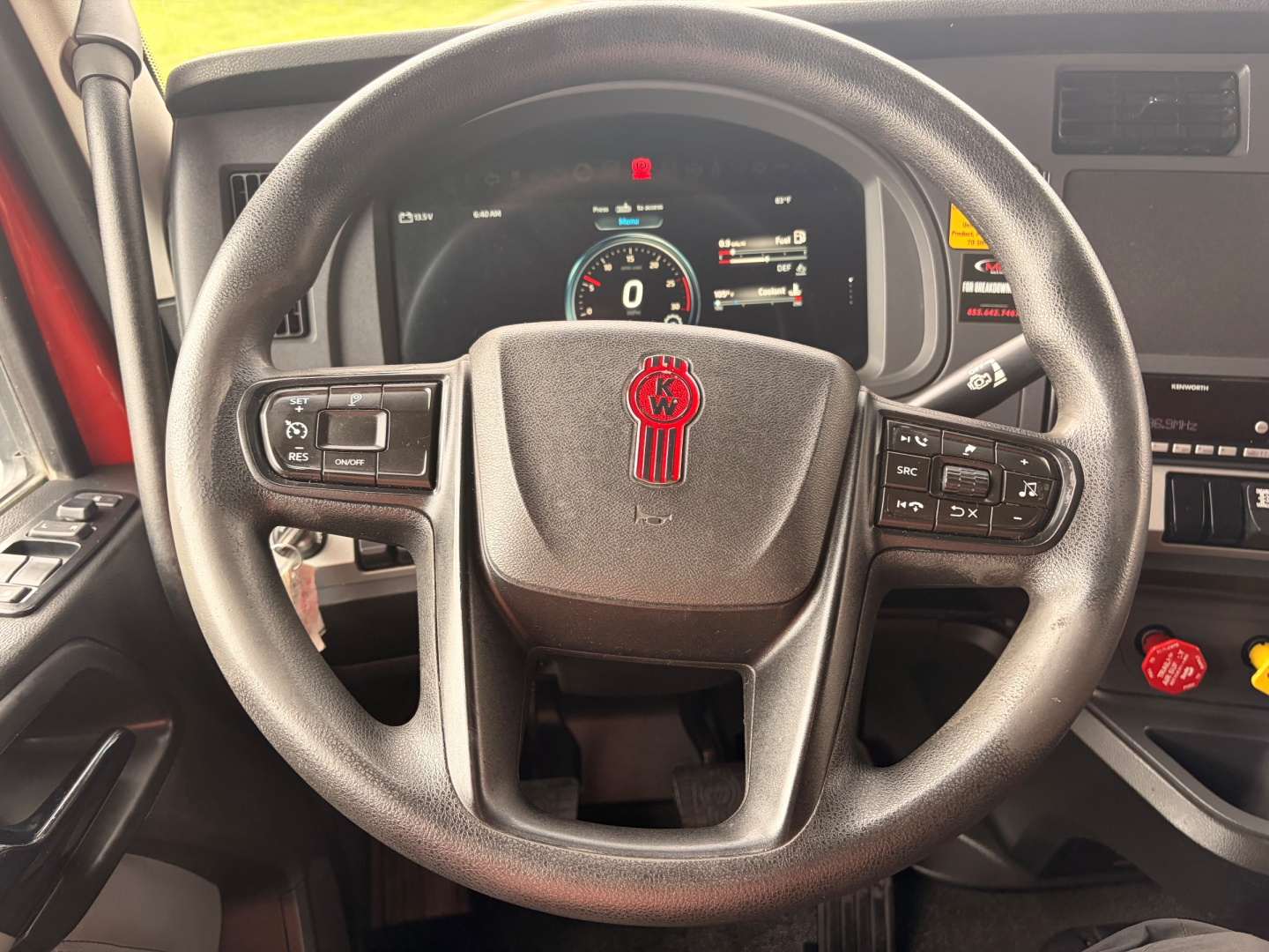 Steering wheel and instrument cluster of a Kenworth T680 truck showing digital gauge display and controls on steering wheel.