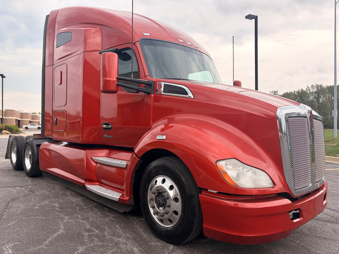 Kenworth T680 truck in red showing front and cab area with sleeper, chrome grille, and dual rear axles.