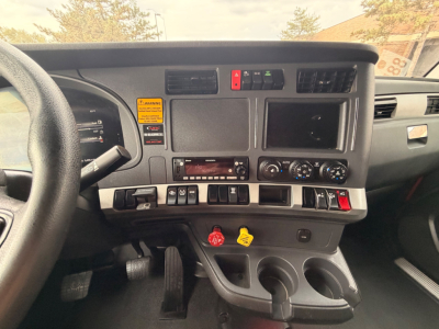 Kenworth T680 dashboard view showing steering wheel, instrument cluster, center console with climate controls, diagnostic switches, and cup holders.