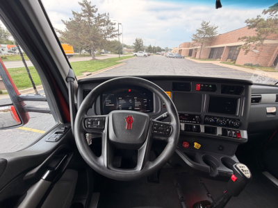 Dashboard and steering wheel of a Kenworth T680 truck cab, with instrument cluster, center console, and gear selector visible.