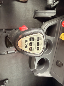 Truck interior showing a gear shifter with P R N D 2 1 labeled 'EATN' and ignition area; pedal visible; circular cup holders and dashboard controls.