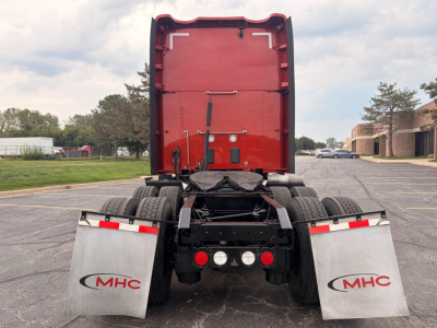 Rear view of a red Kenworth T680 tractor with MHC mud flaps showing two red taillights, dual rear wheels, and black chassis.