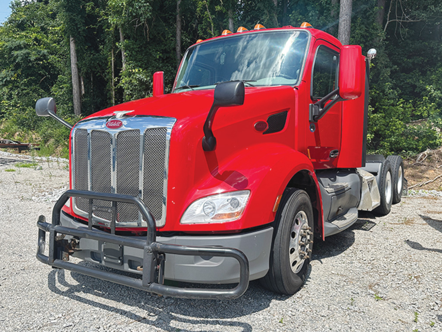 Peterbilt 579 truck in red, front view with grille guard and dual rear axles.