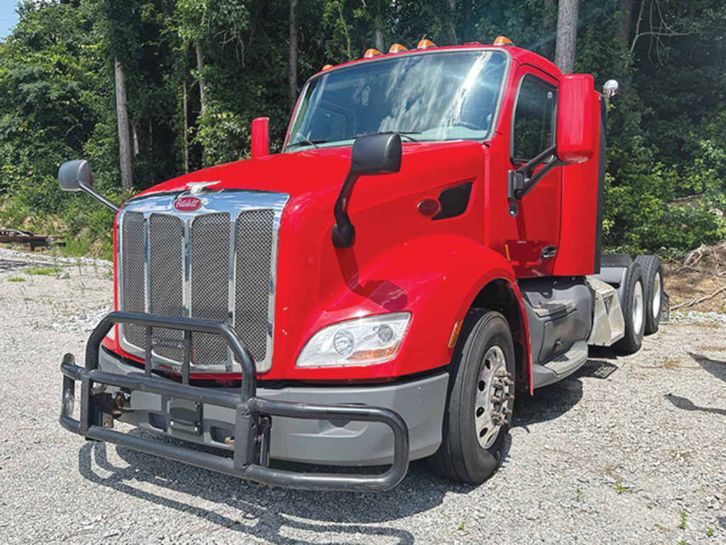 Peterbilt 579 truck in red, front view with grille guard and dual rear axles.