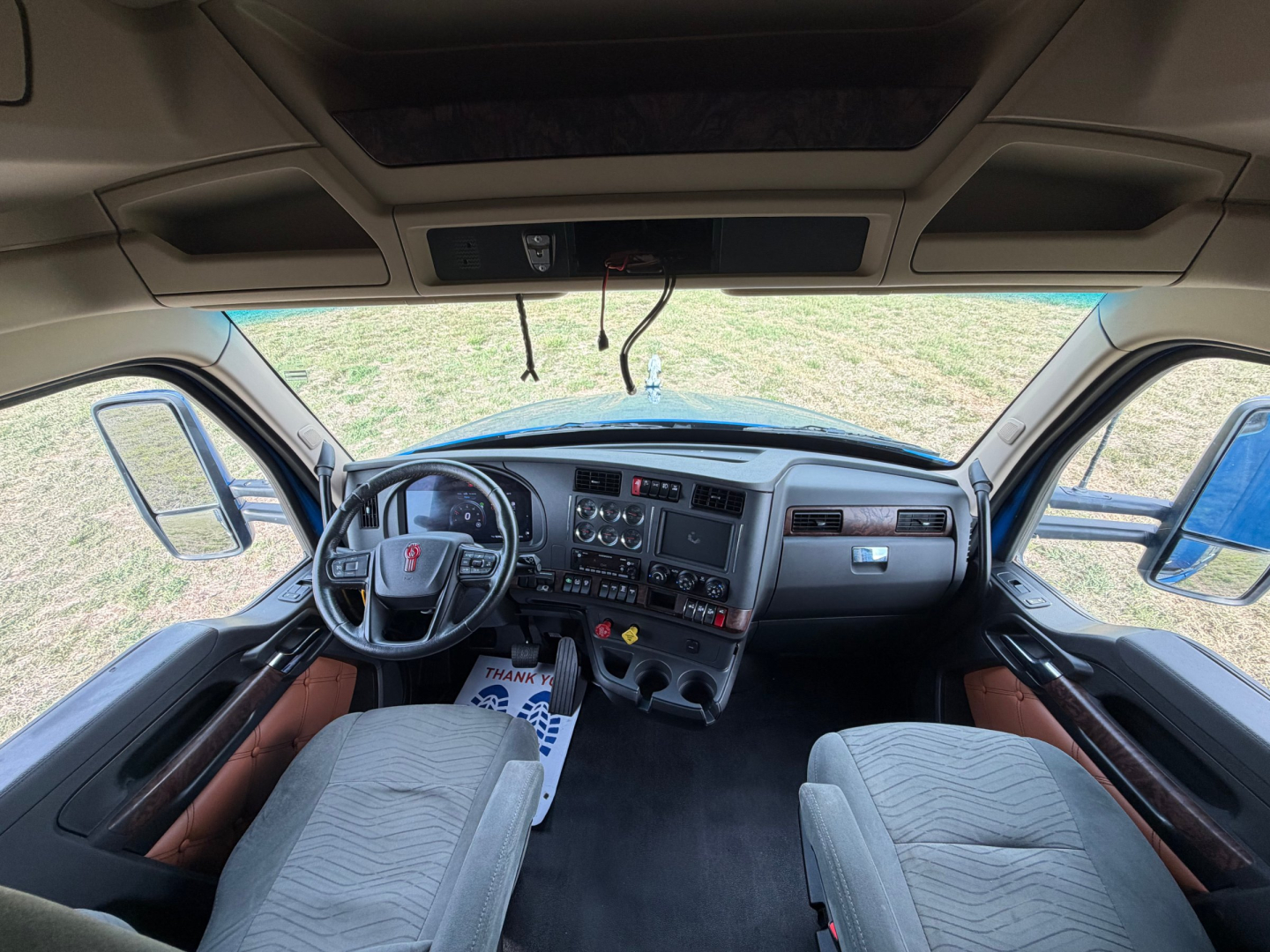 Kenworth T680 truck interior dashboard view with steering wheel, central console, and driver seats.