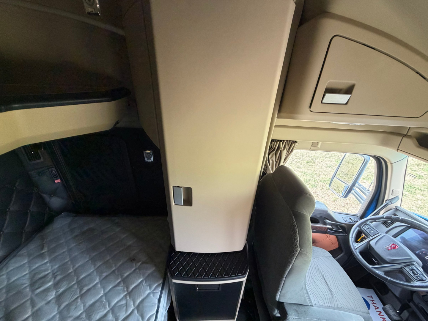 Kenworth T680 truck interior cockpit and sleeper area with elevated cab storage cabinet and driver's seat view.
