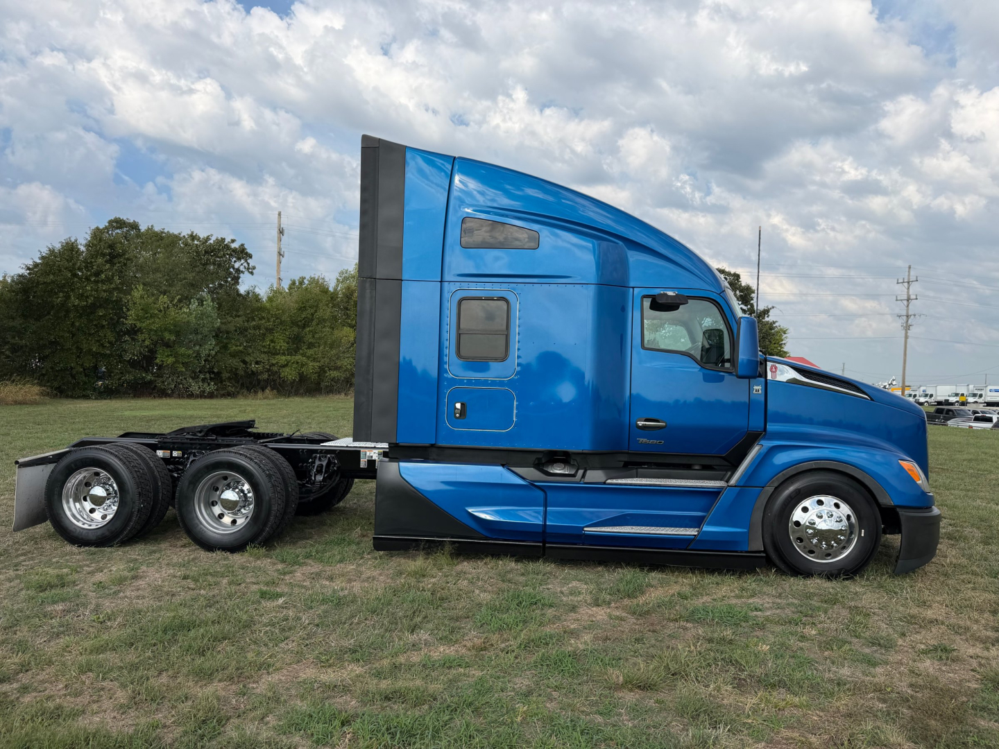 Kenworth T680 tractor cab side view showing blue exterior and wheel configuration.