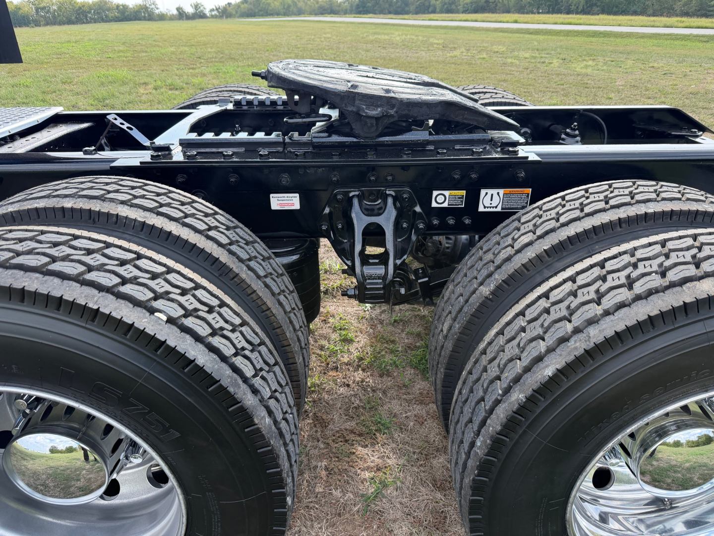Kenworth T680 remote view showing tandem axle area with dual rear wheels and fifth wheel chassis center.