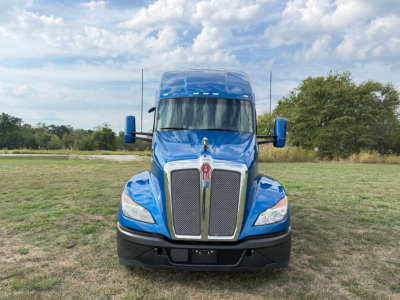Front view of a blue 2024 Kenworth T680 conventional sleeper truck showing grille, hood, headlights, and side mirrors.