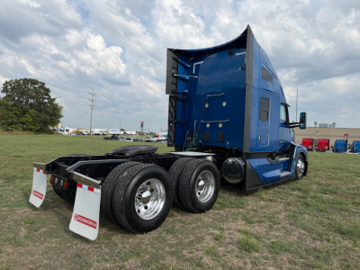 Kenworth T680 semi-truck cab in blue, rear view shows dual rear axles and fifth-wheel mount, with white mud flaps and chrome wheels.