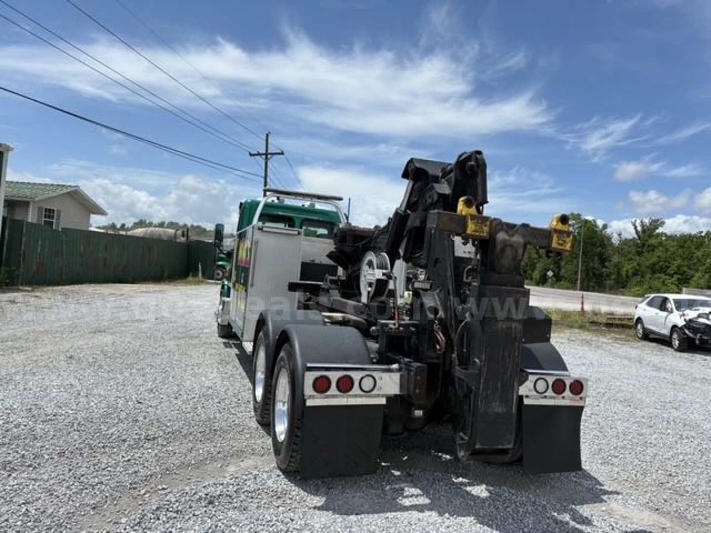 Front and rear view of a Freightliner Cascadia 113 tow truck with a hydraulic rollback bed and lifting arms.