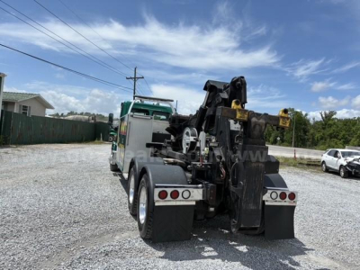 Front and rear view of a Freightliner Cascadia 113 tow truck with a hydraulic rollback bed and lifting arms.