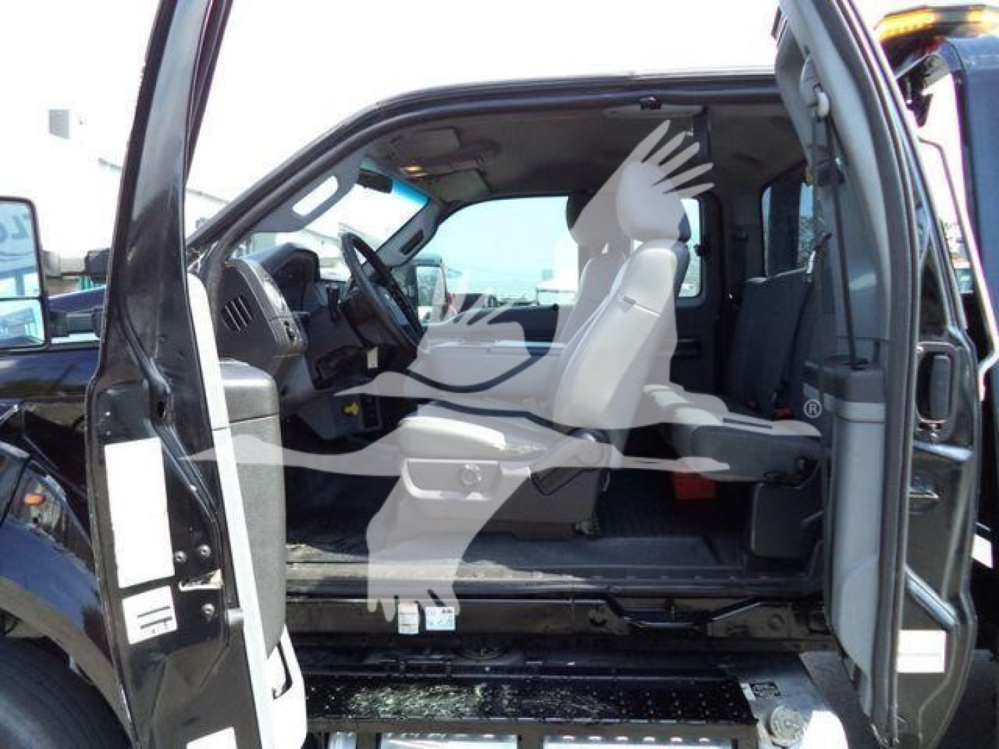 Ford F650 cab interior view showing front driver seat and open door with dashboard and steering wheel; light-colored seats and step area visible