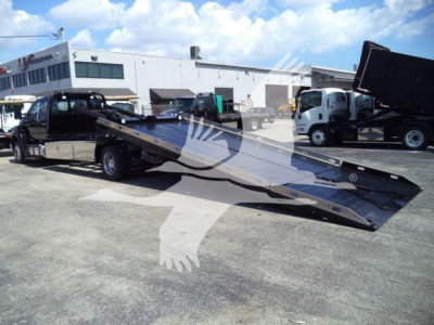 2017 Ford F650 rollback tow truck flatbed with ramp extended and other trucks in background.