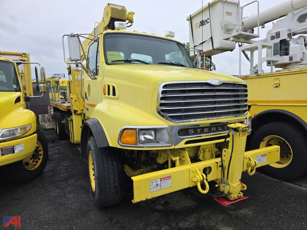 Yellow Sterling LT8500 crane truck from front view with telescopic boom and hook block, grille and bumper in focus.