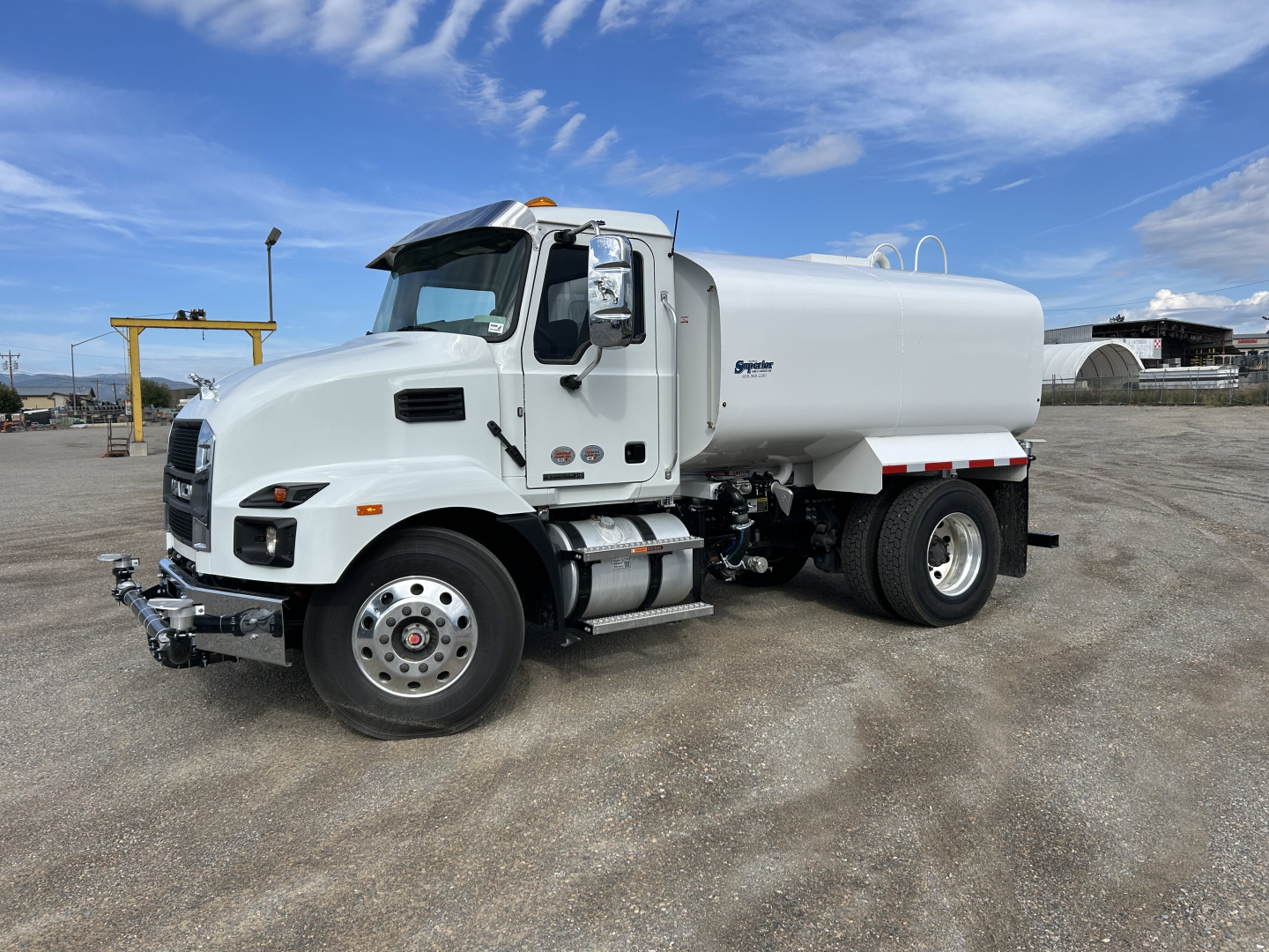White Mack MD7 medium-duty truck with a cylindrical tanker body, front chrome bumper, dual rear wheels, and fuel tanks along the side.