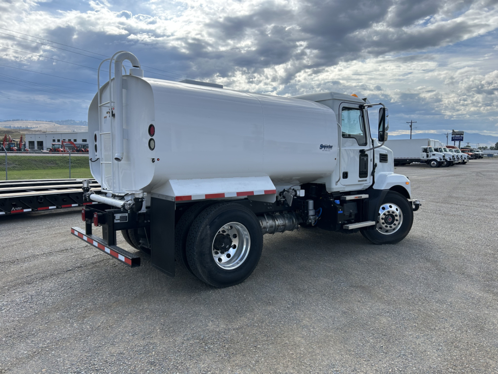 Truck rear/side view of a white 2025 Mack MD7 vacuum/oil-transfer truck with cylindrical tank, rear ladder, and dual rear wheels.