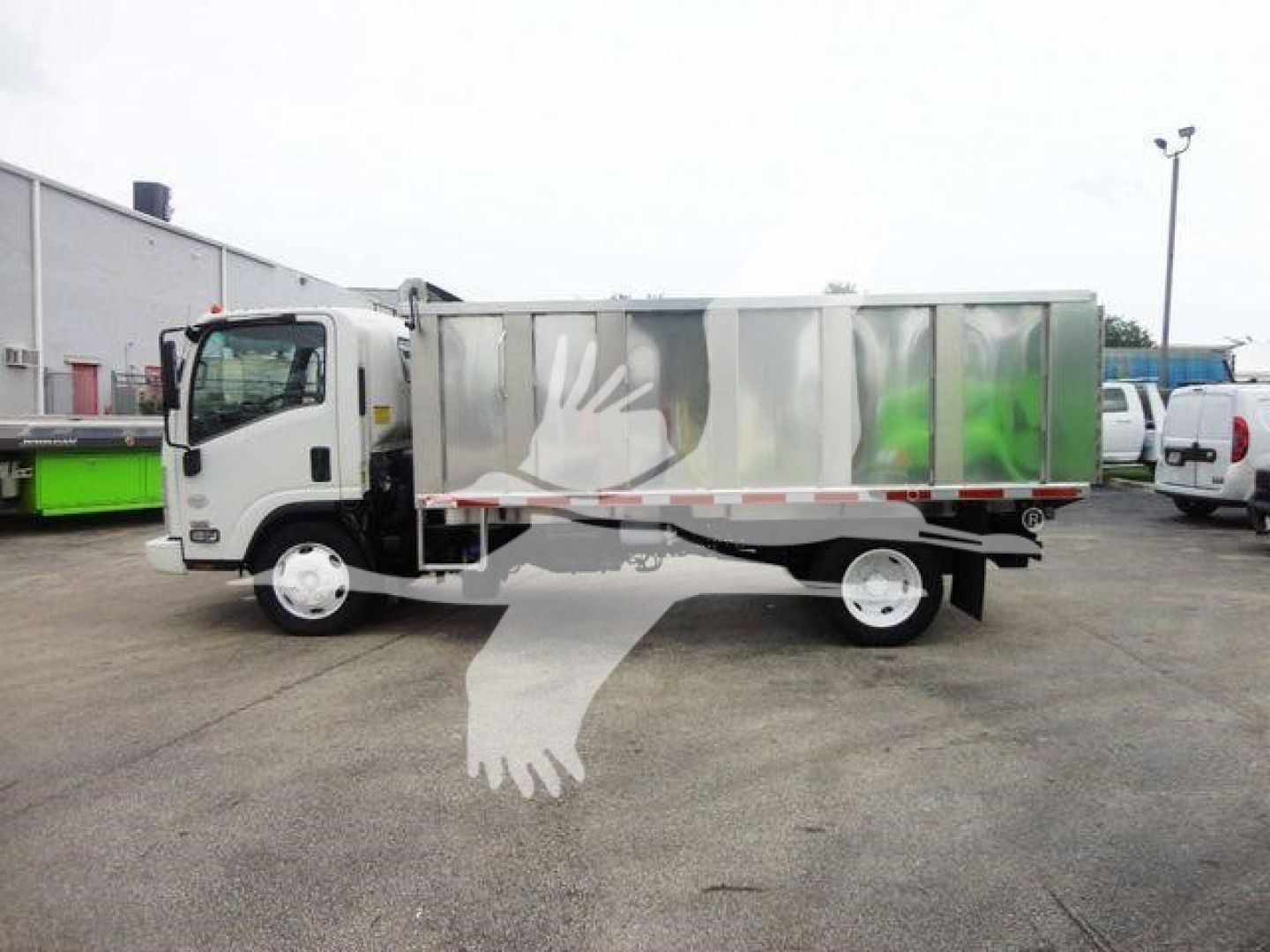 Isuzu NPR/NQR dump truck side view with metal dump bed and logoed sides. Visible text not legible; truck in a dealership lot.