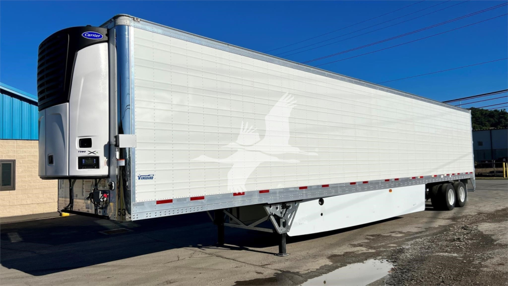 Trailer side view of a 2023 Vanguard reefer trailer showing a white cargo box, blue frame, and refrigeration unit at front left.