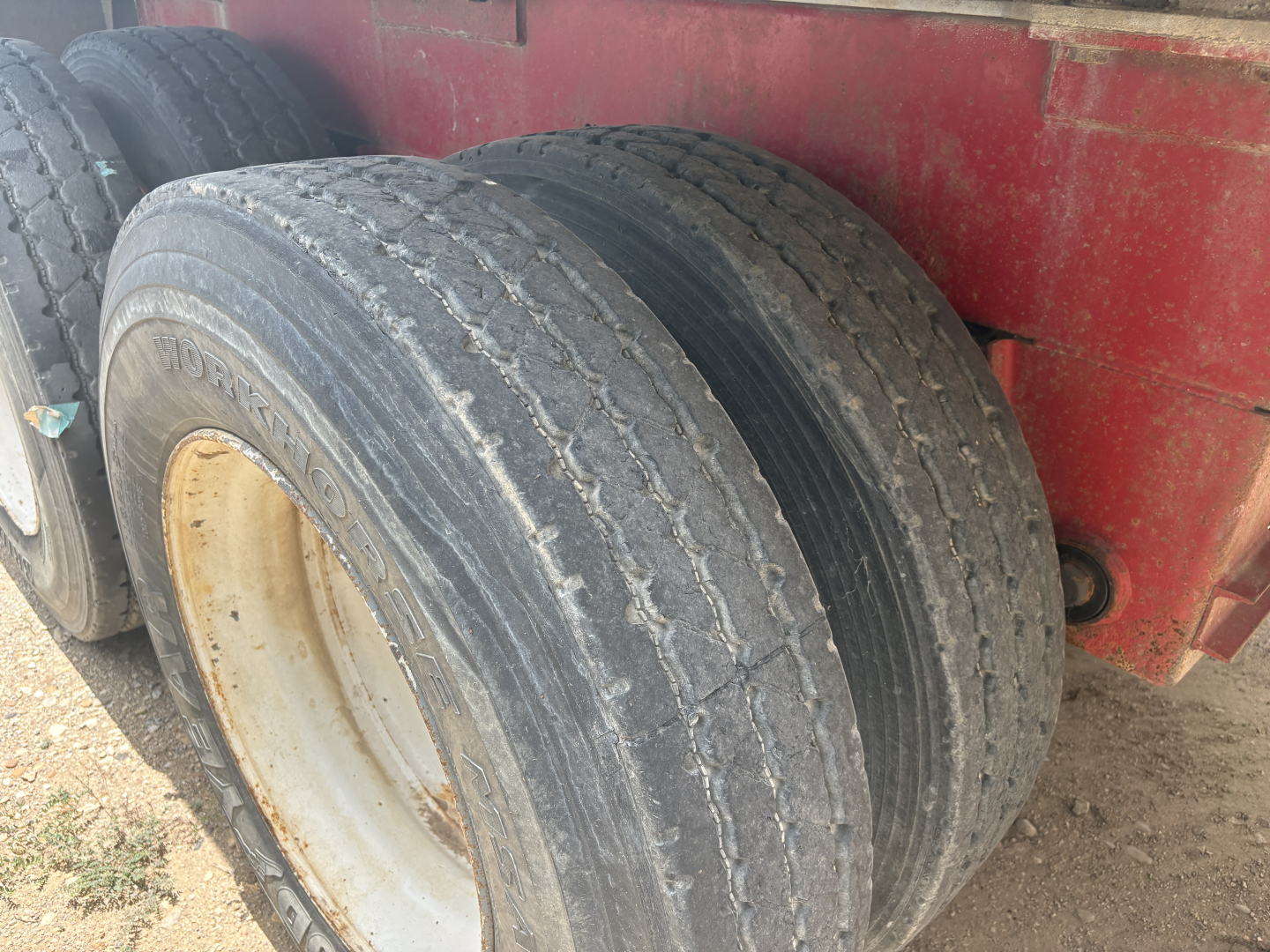 Trailer wheel assembly showing dual tires with visible tread and white rims on a red trailer, part of a 2012 Dragon 150BBL used trailer listing.