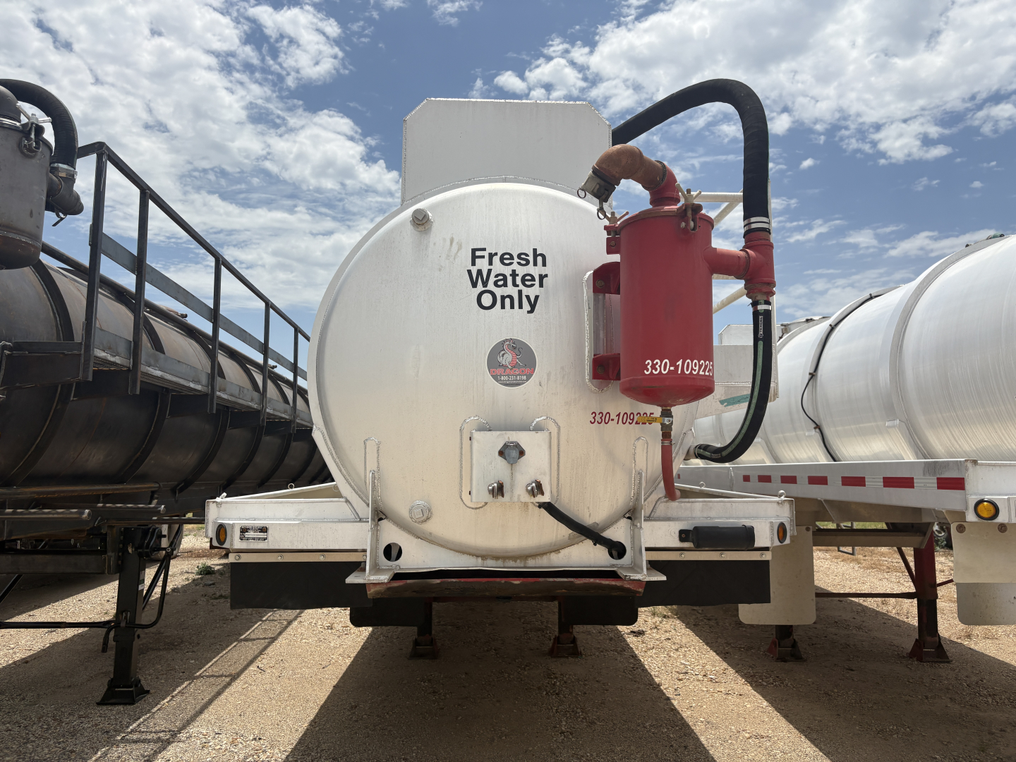 Vacuum trailer rear showing white cylindrical tank with Fresh Water Only label and red drain assembly mounted on the back.
