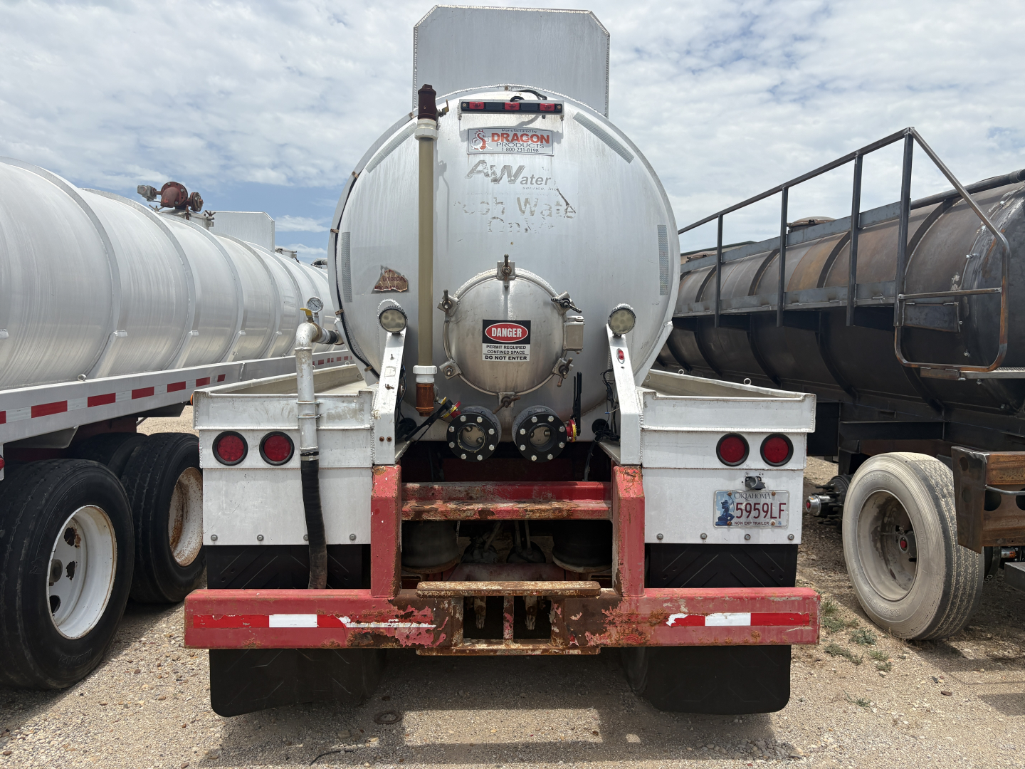 Rear view of a 2012 Dragon 150BBL vacuum trailer showing cylindrical tank and rear bumper with red accents; stickers and license plate visible.