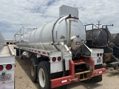 Tank trailer with cylindrical stainless steel tank on dual rear axles, elevated ladder on left, rear bumper with red and white reflective tape, circular access hatch, and a small black diesel tank behind. Visible text: some illegible markin