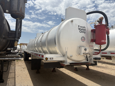 Vertical cylindrical seaworthy tanker trailer showing Fresh Water Only label and safety device on rear with red fire extinguisher. 2012 Dragon 150BBL vacuum trailer.