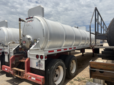 Vacuum trailer tank in-service showing cylindrical aluminum tank mounted on dual-axle chassis with rear bumper and license plate.