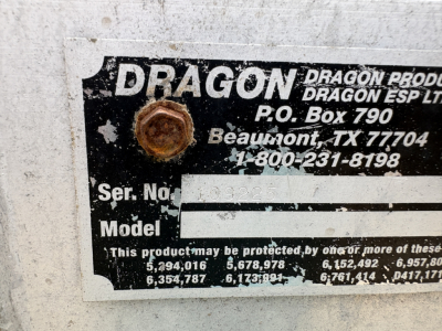 Dragon brand trailer plate showing model/serial fields and contact info, with a rusted bolt securing the label.