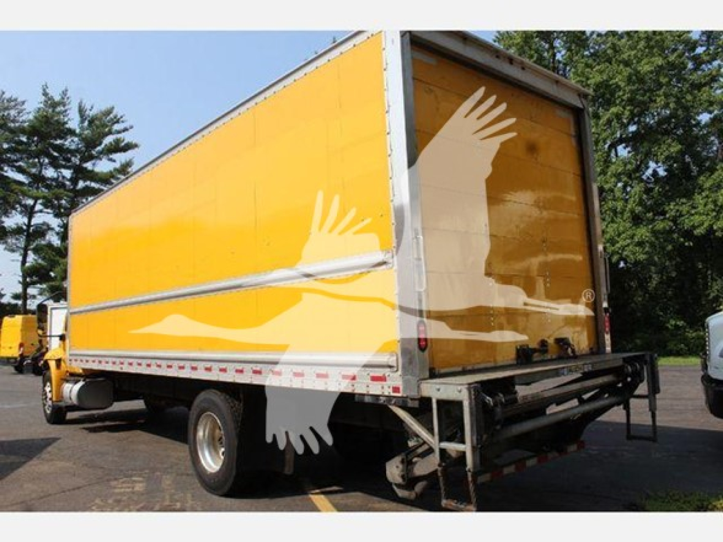Box truck with yellow trailer showing rear view, white wings graphic on side, rear bumper, and taillights.