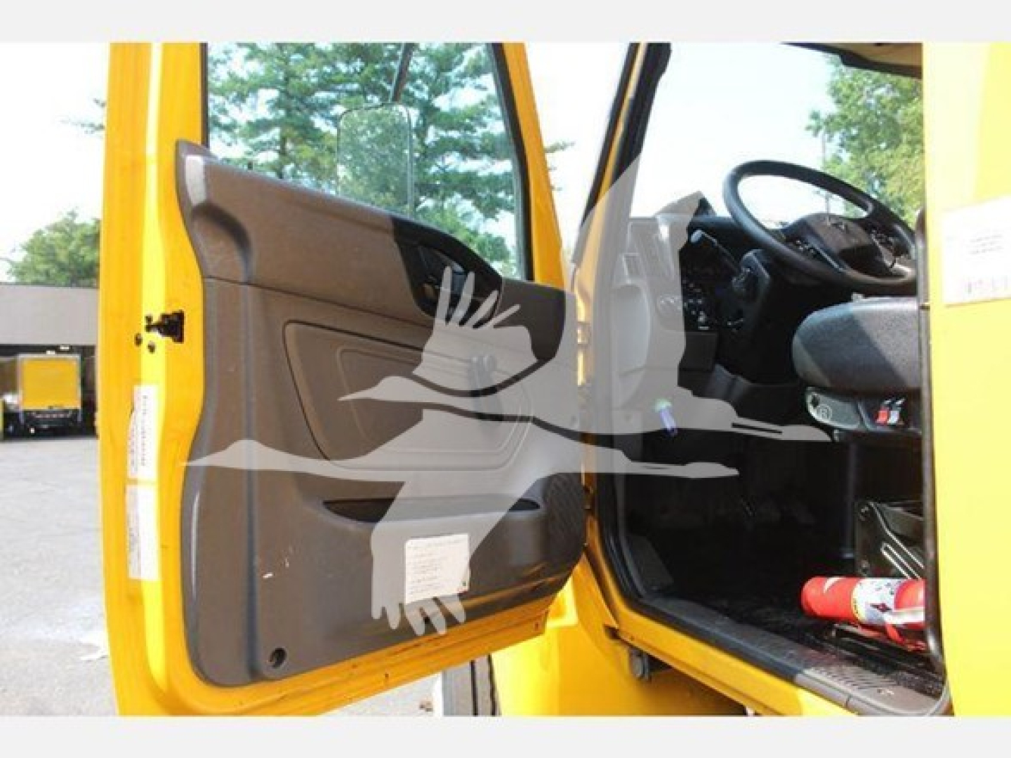 Truck cab interior door panel and driver seat area of a 2020 International MV box truck, open door showing steering wheel and dashboard.