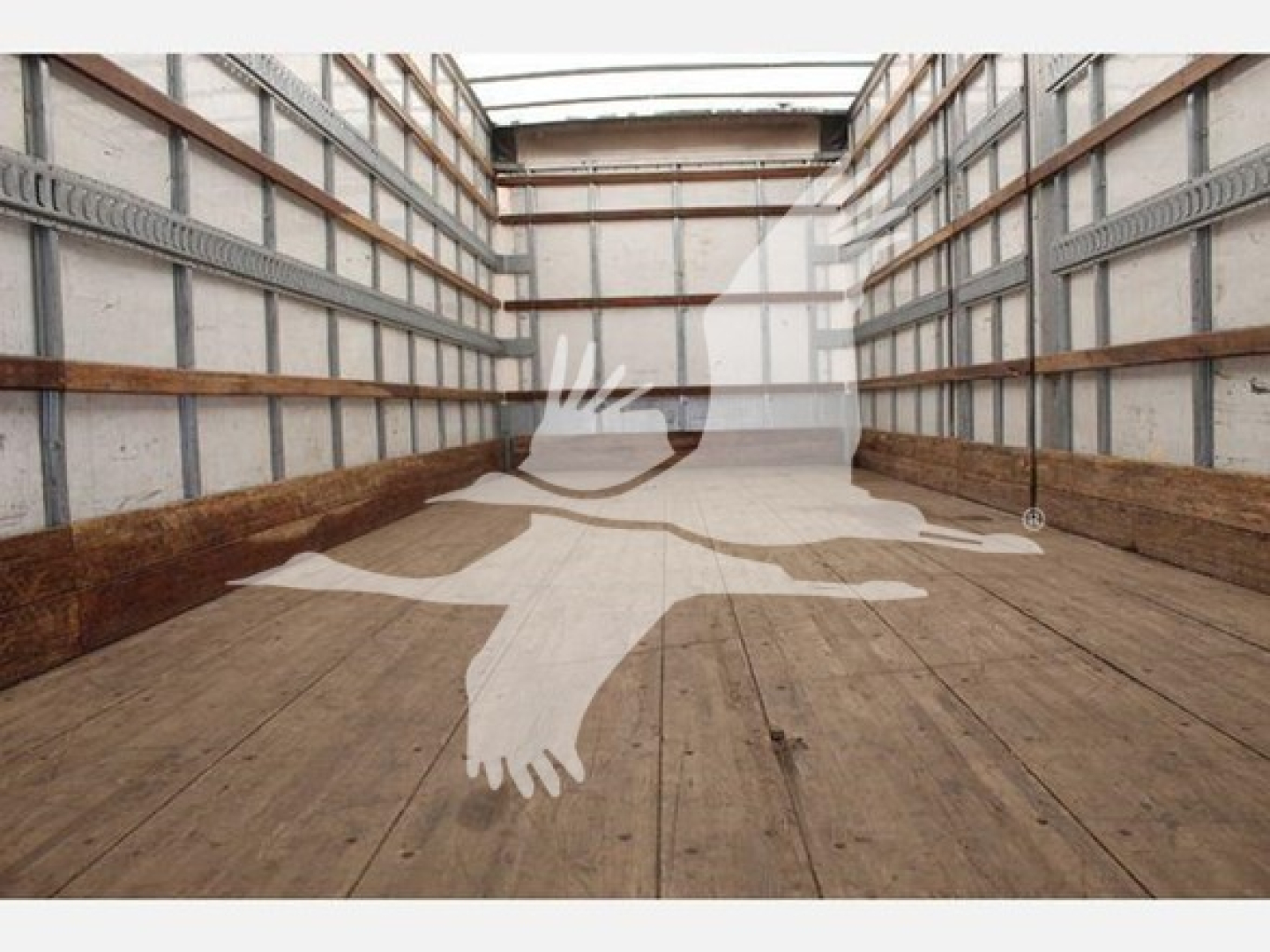 Truck interior cargo area showing empty wooden floor and metal side walls with rails; watermark of a flying bird silhouette overlay.