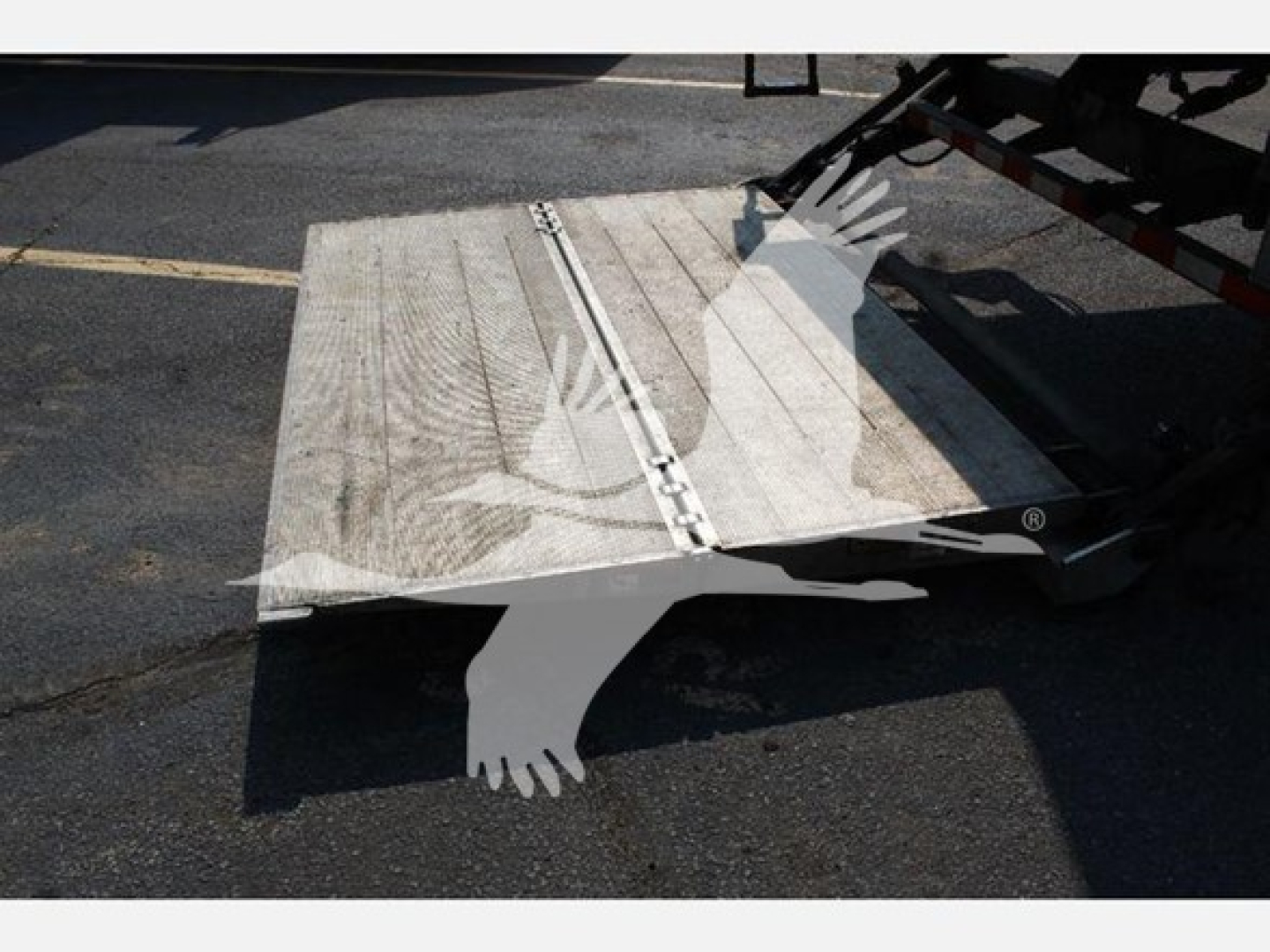 Truck ramp/loading deck extended from a box truck with metal surface, side rails and hinge mechanism visible.
