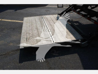Truck ramp/loading deck extended from a box truck with metal surface, side rails and hinge mechanism visible.