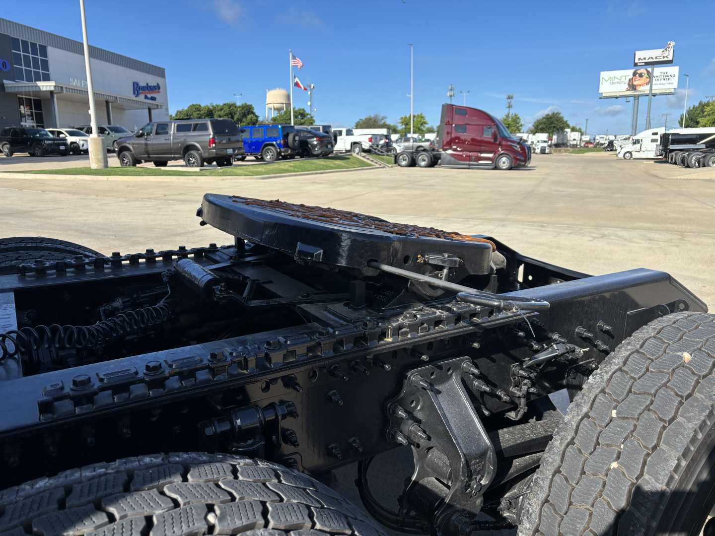 Mack PR64T76H tractor shows chassis and fifth wheel coupling with visible chains and heavy-duty tires.