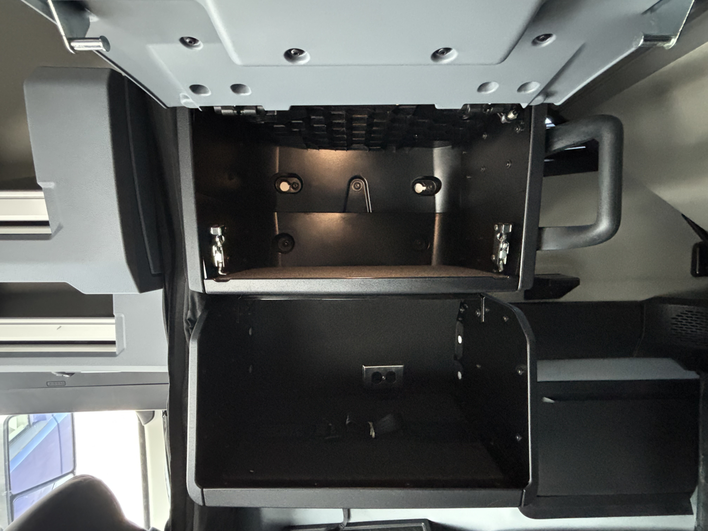 Truck cab area showing storage compartments under bunk with open drawers and metal framework.