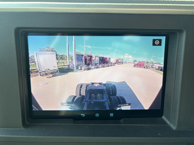 Dashboard display showing a view from the Mack PR64T76H truck cab roof with trailers and yard in the distance.
